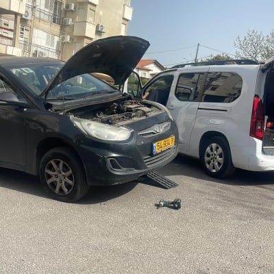 רכב עם מכסה מנוע פתוח וכלי עבודה על הכביש