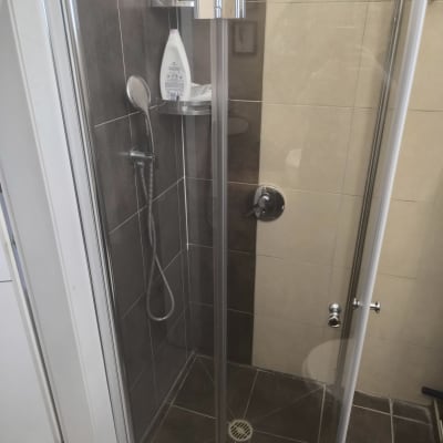 מקלחון עם בקבוקי שמפו וסבון על מדף