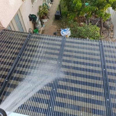 השקיית גג עם צינור מים ליד גינה ועצים