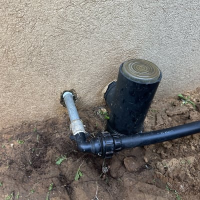 צינור מים מחובר לקיר עם אדמה מסביב