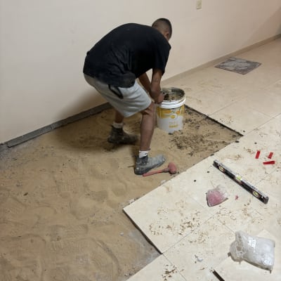 אדם עובד על ריצוף עם כלים וחומרים