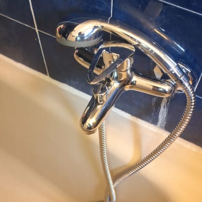 ברז אמבטיה עם צינור גמיש על רקע אריחים כחולים