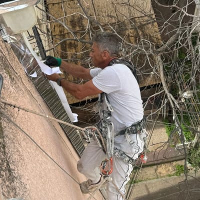 אדם בעבודת גובה על קיר חיצוני עם ציוד בטיחות