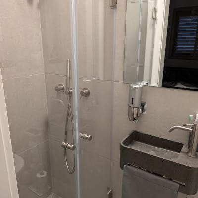 מקלחון זכוכית עם ברזים מודרניים וקיר אריחים