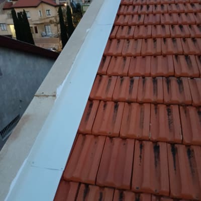 גג רעפים אדומים עם מרזב לבן בצד