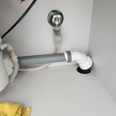 צינור פלסטיק אפור מתחת לכיור עם חיבורי צנרת