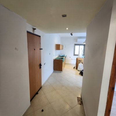 מסדרון עם קירות לבנים, דלת עץ, ארונות מטבח