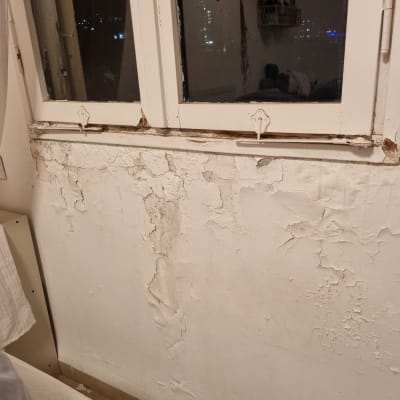 קיר עם צבע מתקלף ליד חלון ישן