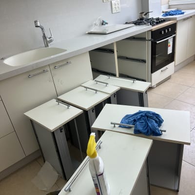 בקבוק חומר ניקוי ומטלית כחולה על דלתות ארון מטבח