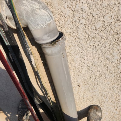 צינור פלסטיק אפור עם חיבור זוויתי על קיר