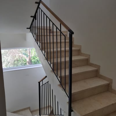 מעקה מתכת שחור עם ידית עץ במדרגות