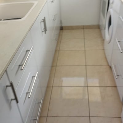 מטבח נקי עם רצפה מבריקה וארונות לבנים