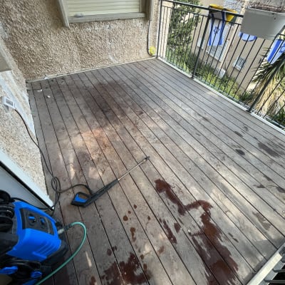מכונת שטיפה בלחץ על רצפת עץ במרפסת