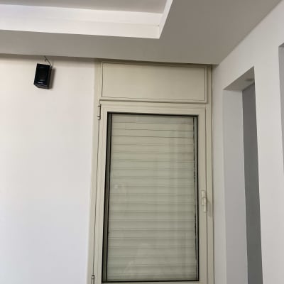 חלון עם תריסים סגורים על קיר לבן