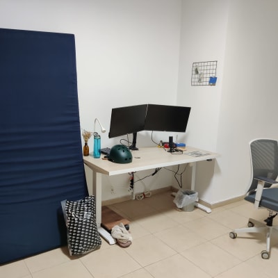 מזרן כחול, שולחן עם מסכים, כיסא משרדי