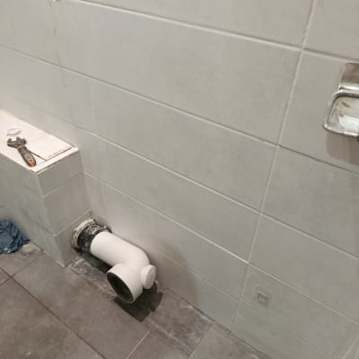 צינור לבן מותקן על קיר אריחים אפור