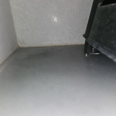 פינה של קיר ורצפה עם חפץ כהה בצד