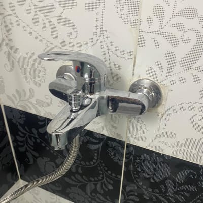 ברז כרום עם צינור גמיש על קיר אריחים