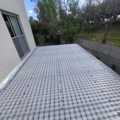 גג פלסטיק גלי מחובר למבנה ליד גינה