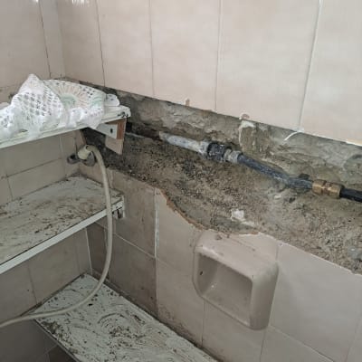 צינור מים חשוף בקיר עם אריחים שבורים