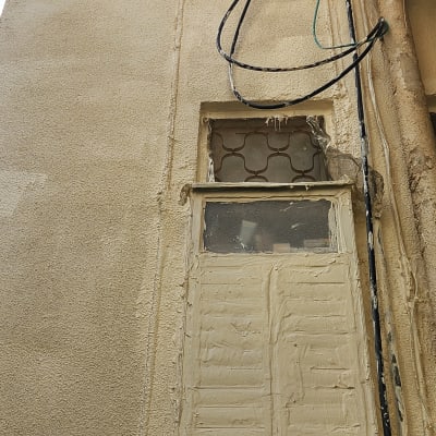 קיר חיצוני עם חלון וחוטי חשמל גלויים