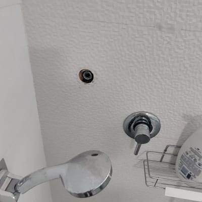 ראש מקלחת וכפתור ברז על קיר אמבטיה