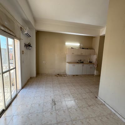 מטבח ריק עם ארונות וקירות חשופים