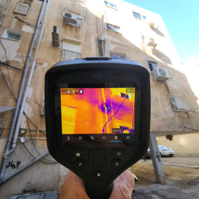 מצלמה תרמית מציגה תמונה של בניין עם דליפות חום
