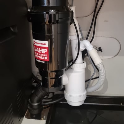 מכשיר טוחן אשפה מתחת לכיור עם צינורות חיבור