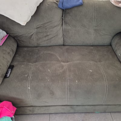 ספה ירוקה עם כתמים ובגדים מפוזרים