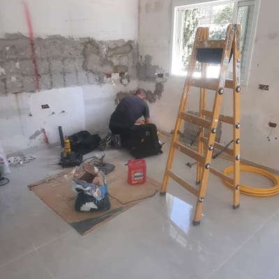 אדם עובד בחדר עם קיר פתוח וסולם