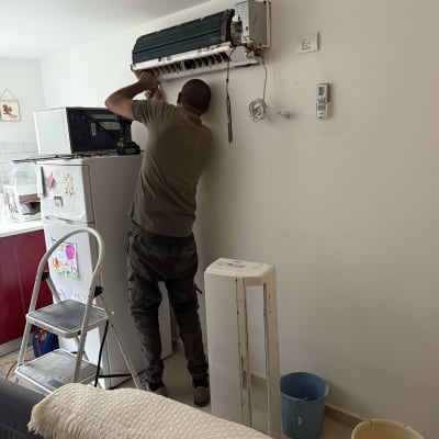 טכנאי מתקין מזגן על קיר בבית