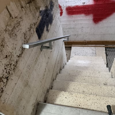 מדרגות עם מעקה מתכת וקיר עם גרפיטי חץ אדום