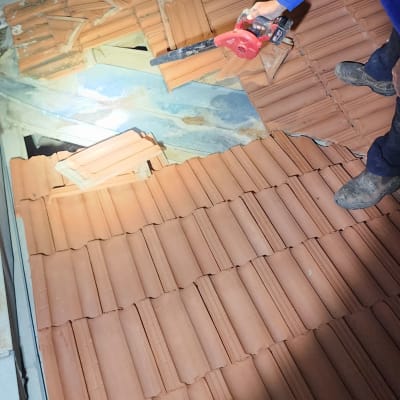 אדם עובד על גג רעפים עם כלי עבודה בלילה