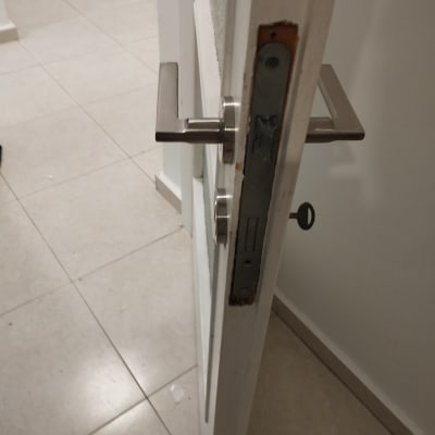 דלת פתוחה עם ידית מתכת ומנעול חשוף