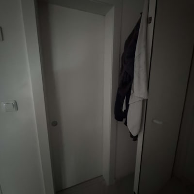 דלת לבנה עם ידית עגולה, בגדים תלויים