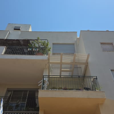 מרפסת עם צמחים ופרגולה בבניין מגורים