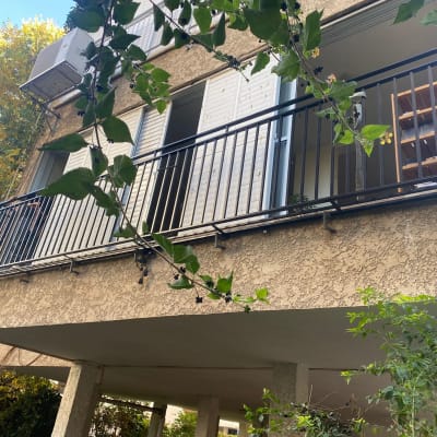 מרפסת עם מעקה מתכת שחור ותריסים לבנים פתוחים