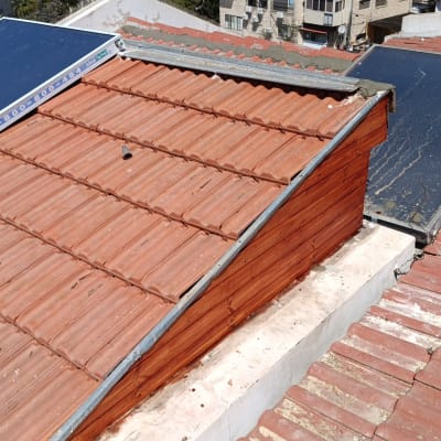 גג רעפים עם קולטי שמש על רקע עירוני