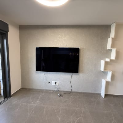 קיר צבוע עם טלוויזיה ומדפים מעוצבים