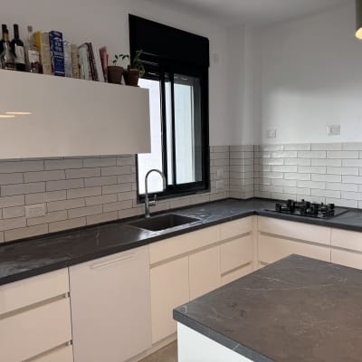 מטבח משופץ עם ארונות לבנים ומשטח עבודה כהה