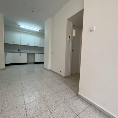 מטבח עם ארונות לבנים ותאורה פלורסנטית