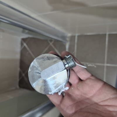 יד מחזיקה חלק מתכת עם הברגה, כנראה חלק אינסטלציה