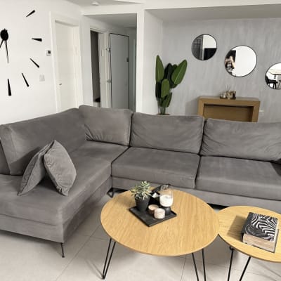 ספה אפורה בחדר מגורים עם שולחנות עץ קטנים