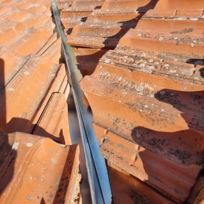 רעפים כתומים עם תעלה מתכתית במרכז הגג