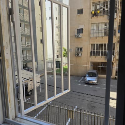 סורג ישר ממתכת בצבע לבן מותקן בחלון דירה