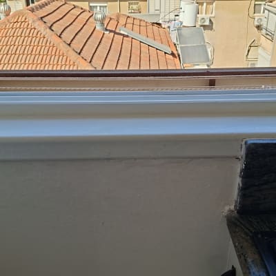 חלון פתוח עם נוף לגג רעפים ומזגן