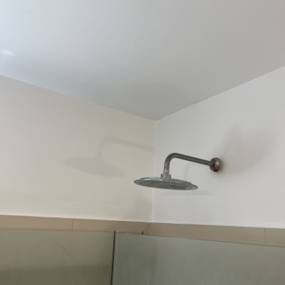 ראש מקלחת מחובר לקיר עם אטימה סביבו