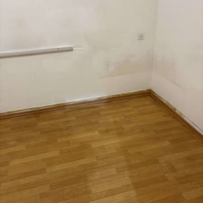 פינה של חדר עם רצפת עץ וקיר לבן