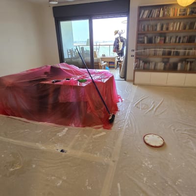 חדר עם רהיטים מכוסים בניילון, מברשת צבע על הרצפה